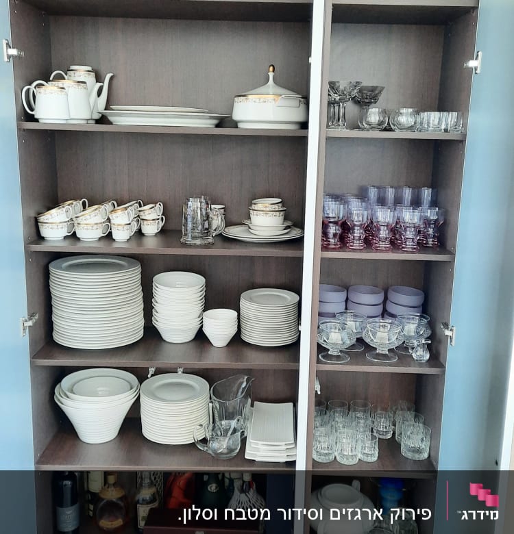 ארון עם כלי אוכל, כוסות וצלחות מסודרים על מדפים